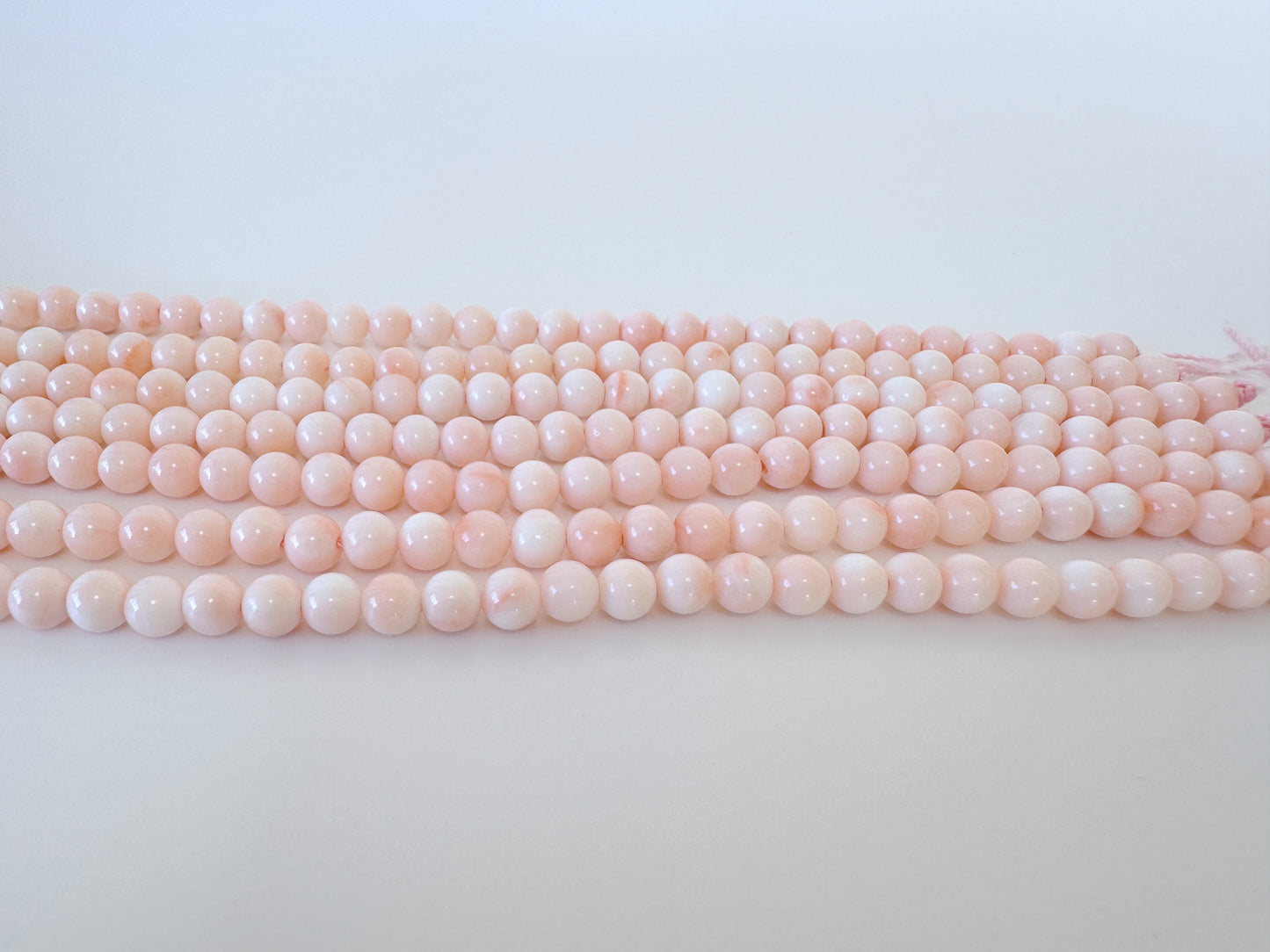 A row of pink and white beads arranged on a white surface.