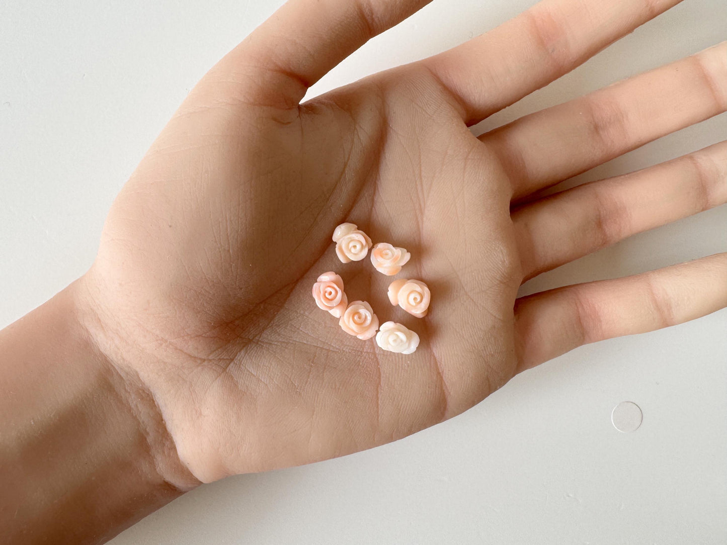 A hand holding six small, pink flower-shaped objects.