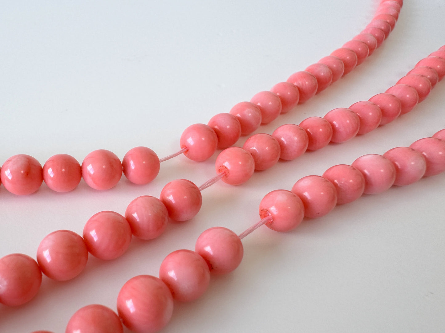 A close-up view of a collection of pink beads arranged in a row, with the focus on the individual beads and their arrangement.