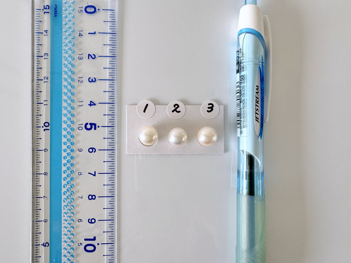 a pen, ruler, and two pearls on a table