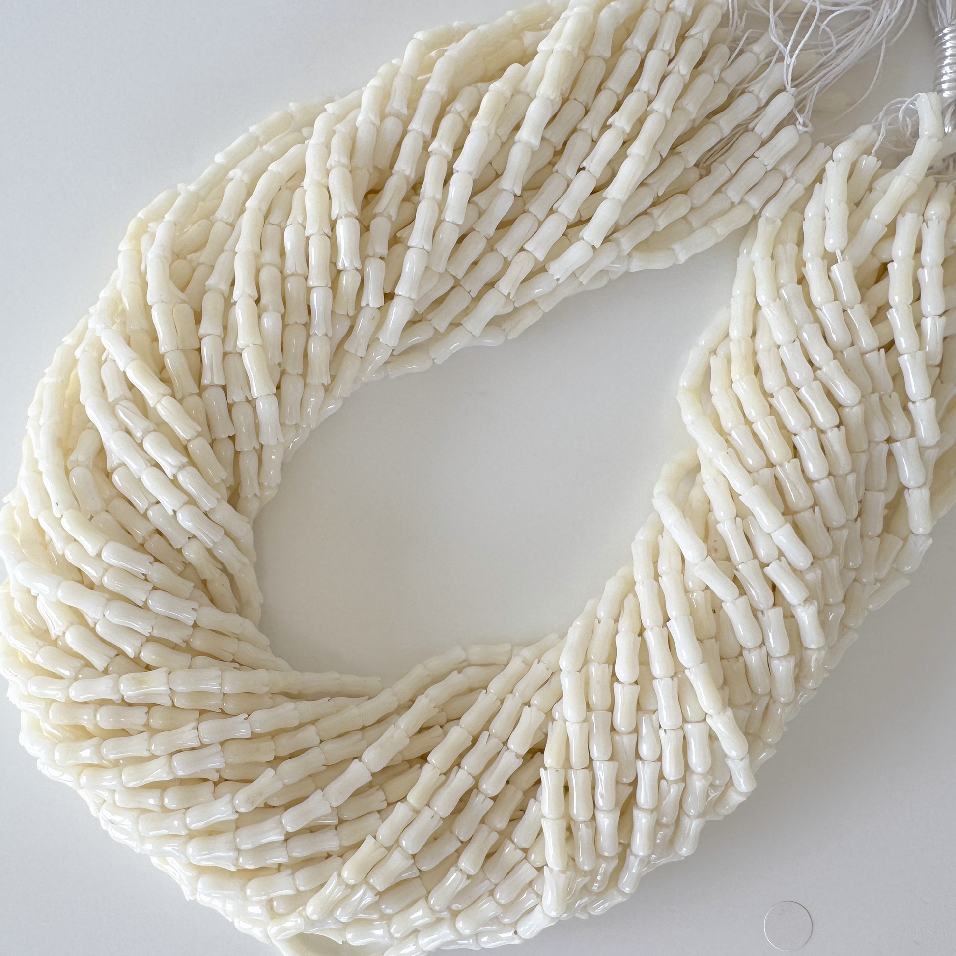 A large, intricate beaded necklace composed of numerous small, white beads arranged in a spiral pattern.