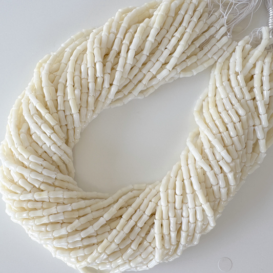 A large, intricate beaded necklace composed of numerous small, white beads arranged in a spiral pattern.