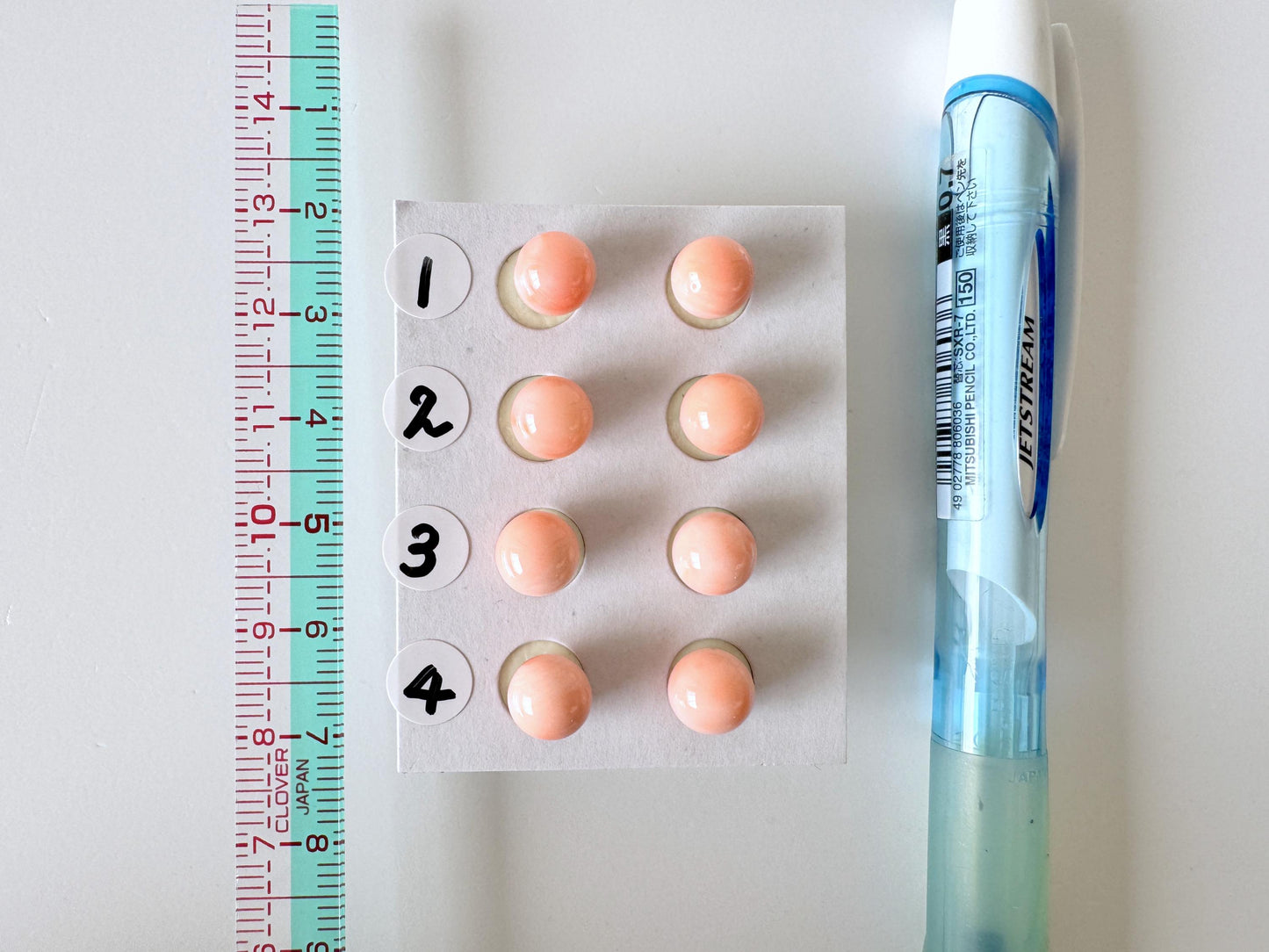 a close-up view of a pill bottle with numbered pills, a ruler, and a blue pen on a white surface.