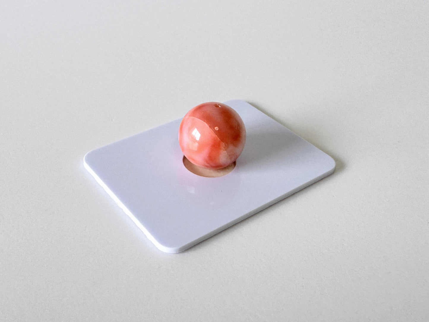 A single, round, red object is centered on a white rectangular surface.