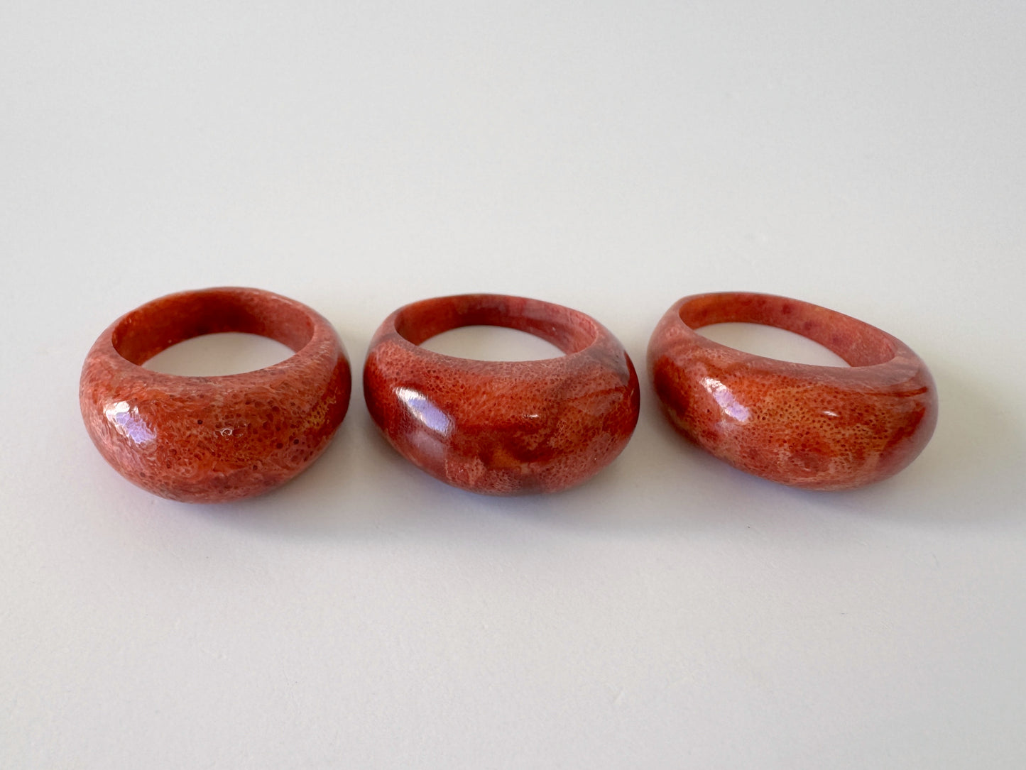 Three red coral-like rings are arranged in a row on a white background.