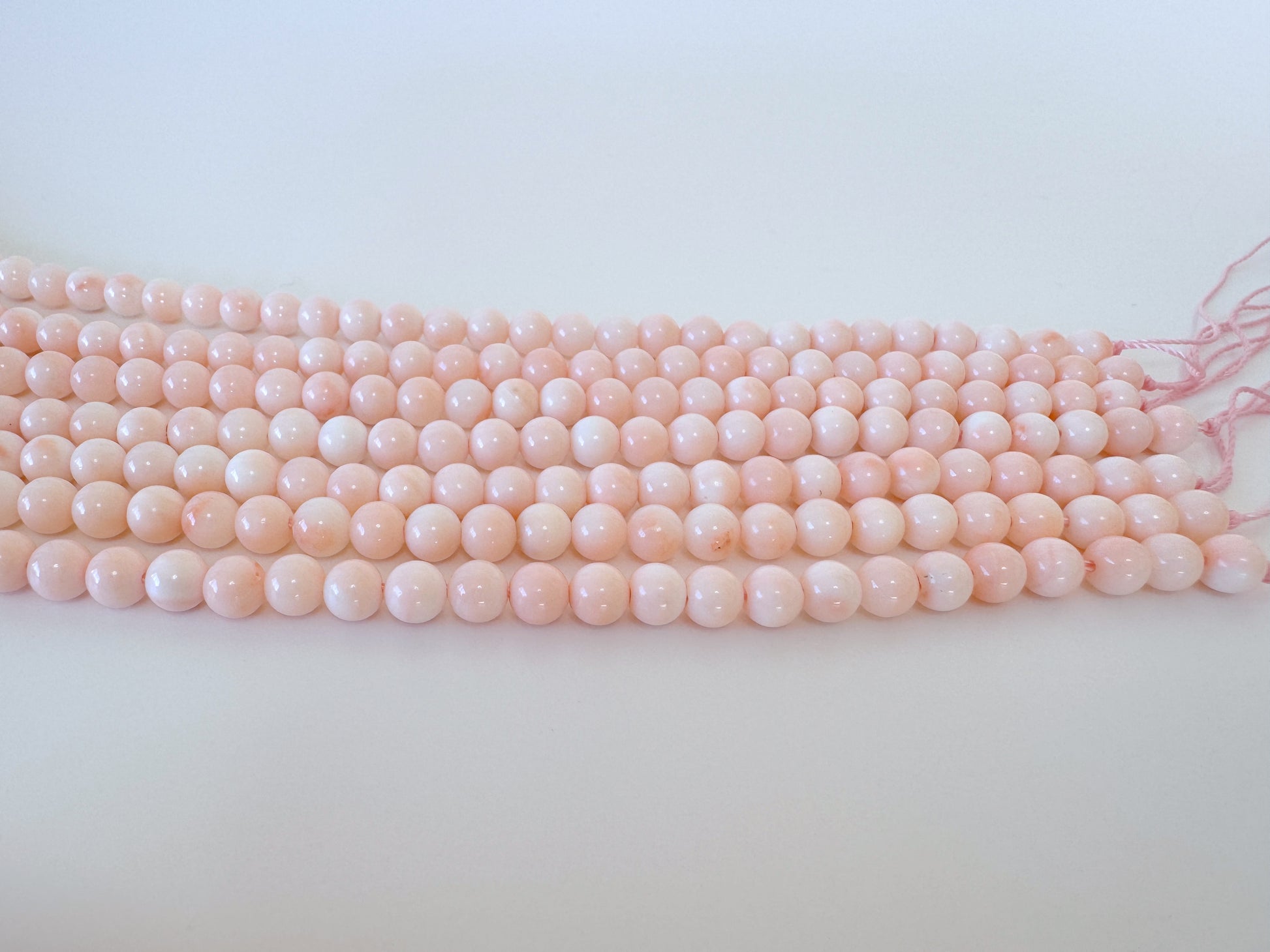 A row of pink coral beads on a white background.