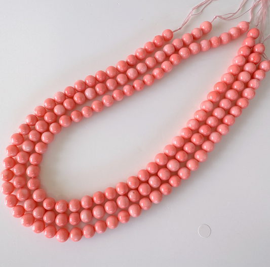 A necklace composed of numerous small, round beads in a vibrant shade of pink.