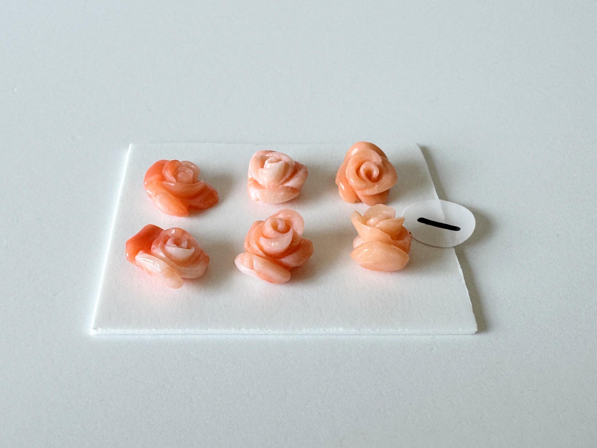 A white square plate with six small, pink and orange rose-shaped objects arranged in two rows of three.