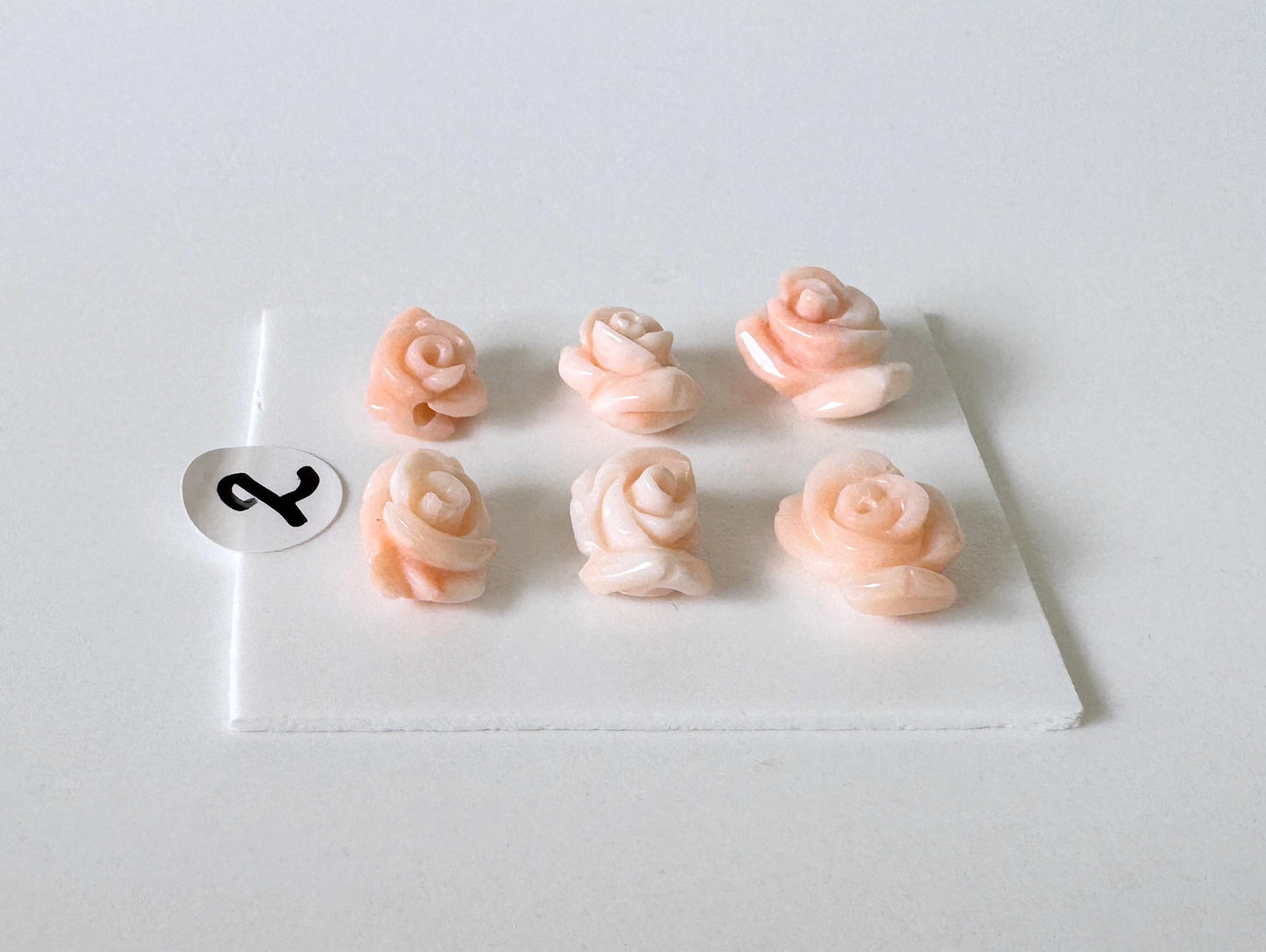 six small, pink rose-shaped objects arranged in a grid on a white surface.