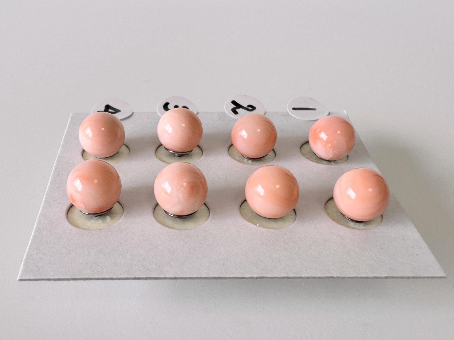 a collection of nine small, round objects arranged in a grid-like pattern on a white surface.