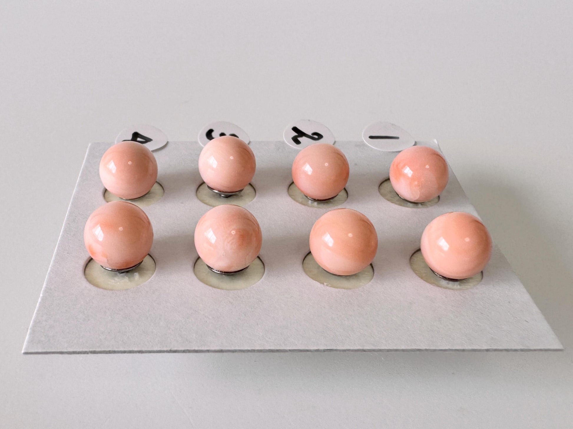 a collection of nine small, round objects arranged in a grid-like pattern on a white surface.