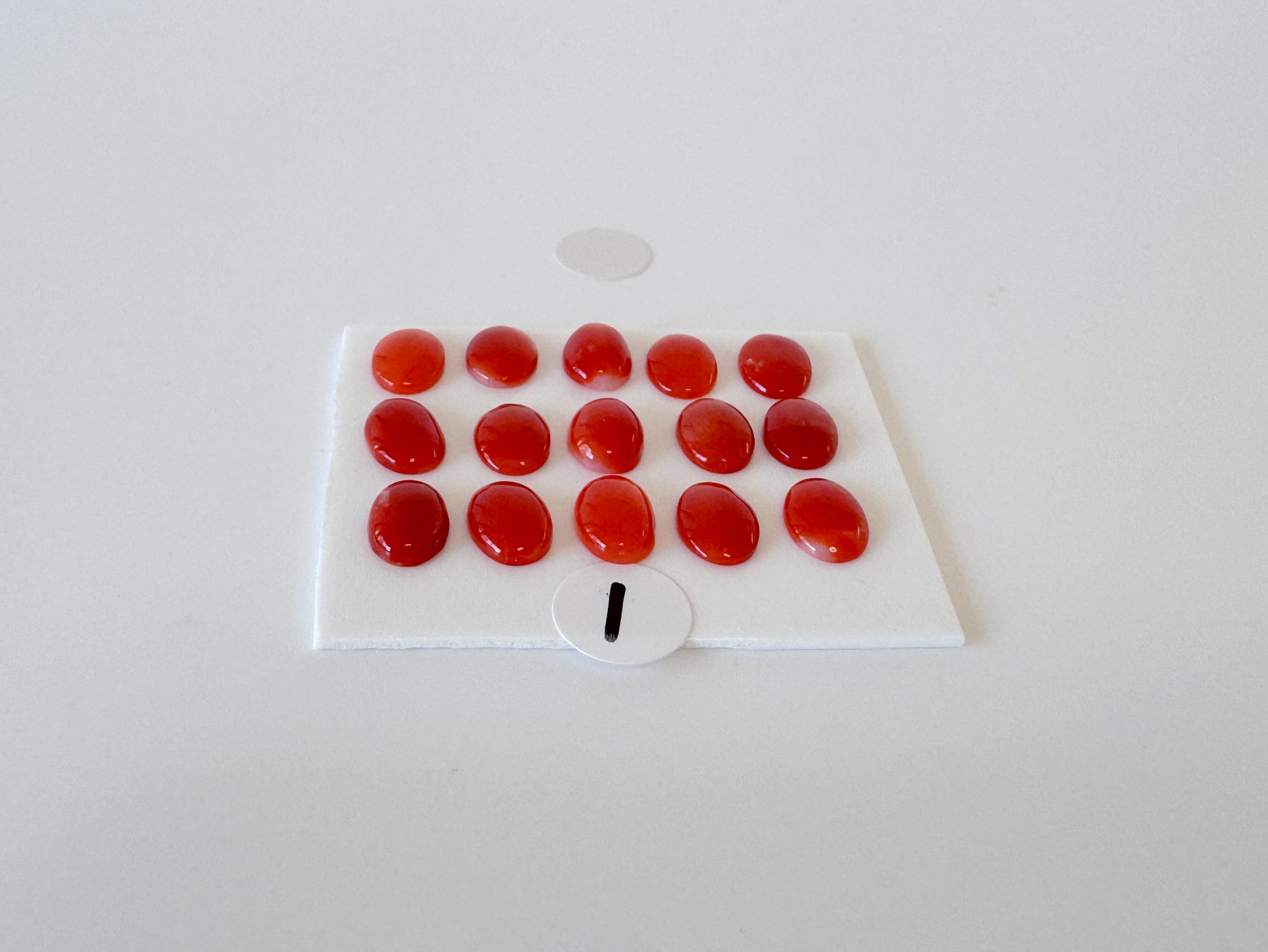 a collection of red gemstones arranged on a white surface, with a small white circle containing the number "1" in the center.