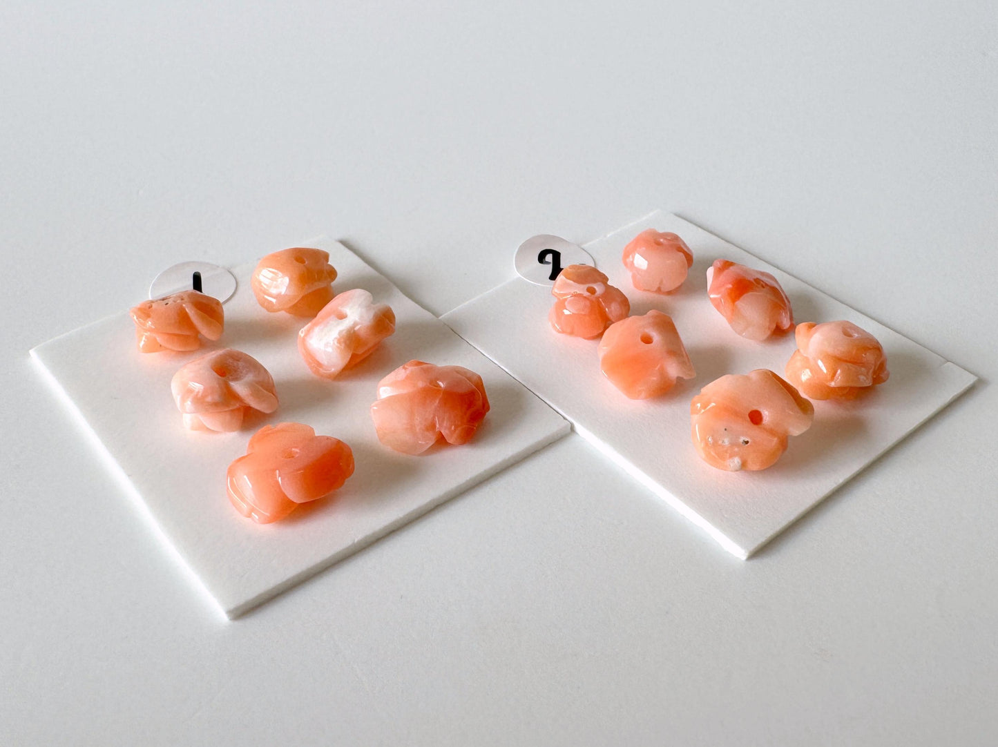 two white plates with small orange objects, possibly beads or candies, arranged on a white surface.