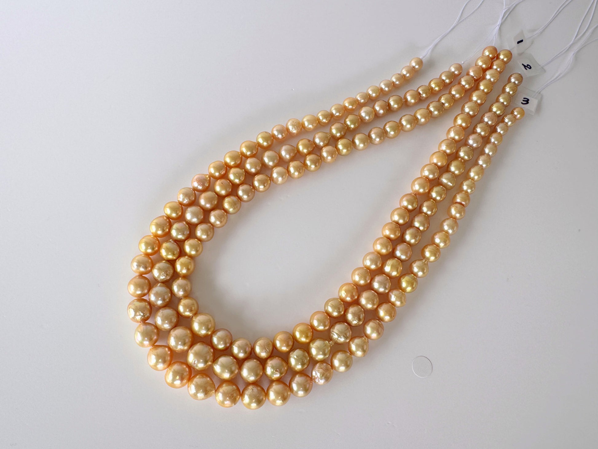 A necklace composed of numerous small, round pearls in a warm yellow color, arranged in a decorative manner.