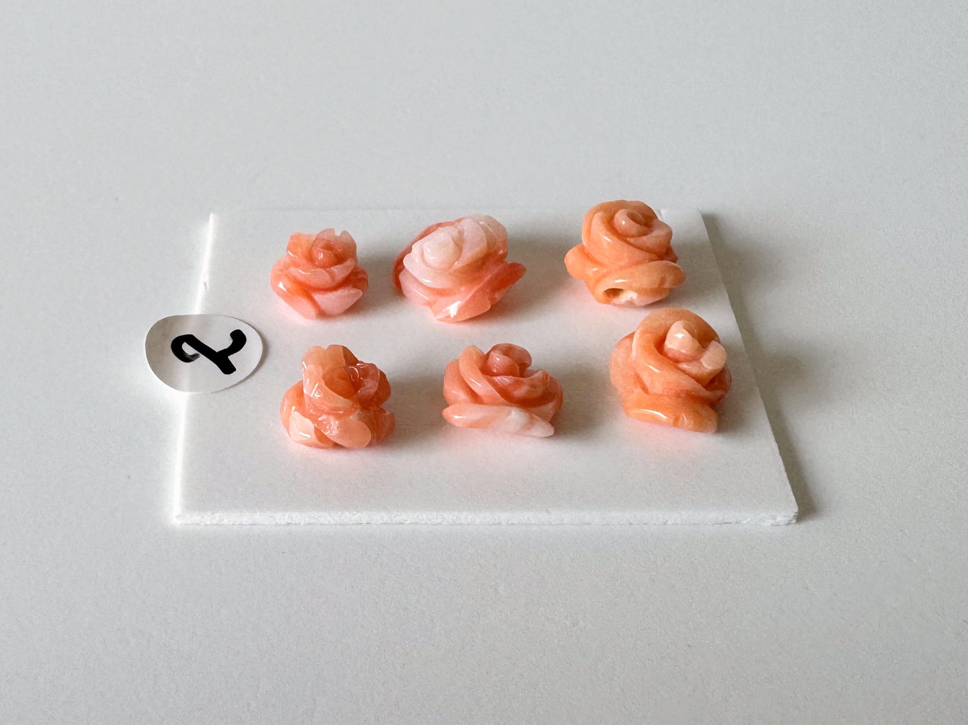 six small, orange-colored objects arranged in a grid-like pattern on a white surface.