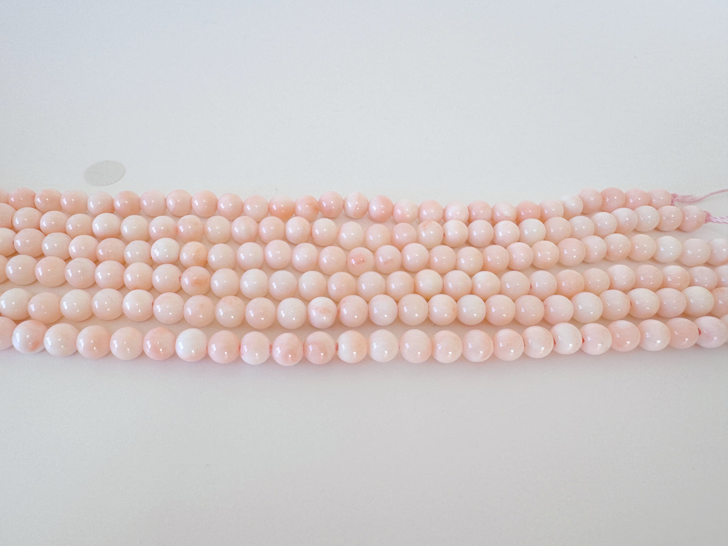 A row of pink coral beads on a white background.