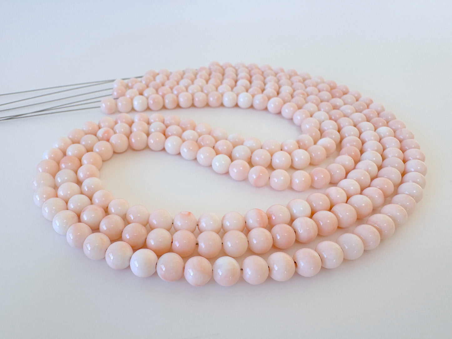 A long, delicate necklace made of small, round, pink beads arranged in a circular pattern.