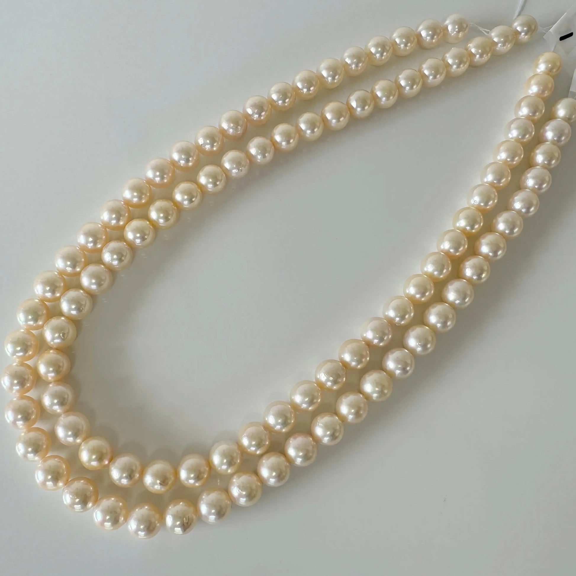 A necklace made of white pearls is displayed on a white surface.