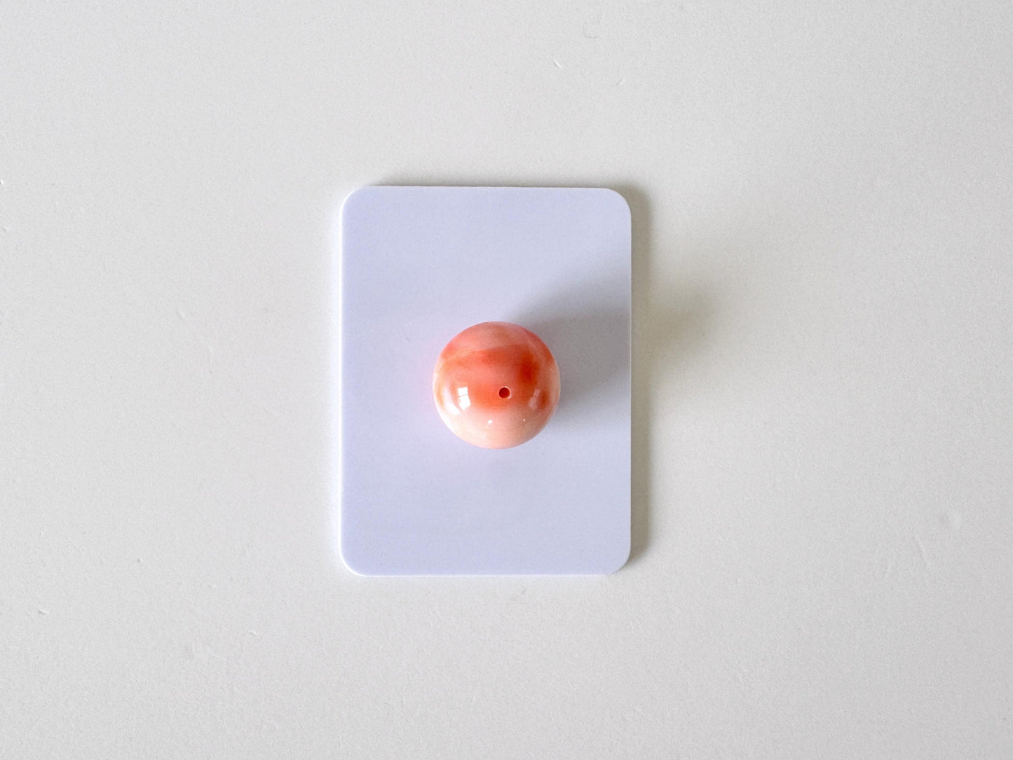 a single, small, round object, which appears to be a small, round, pink object, placed on a white surface.