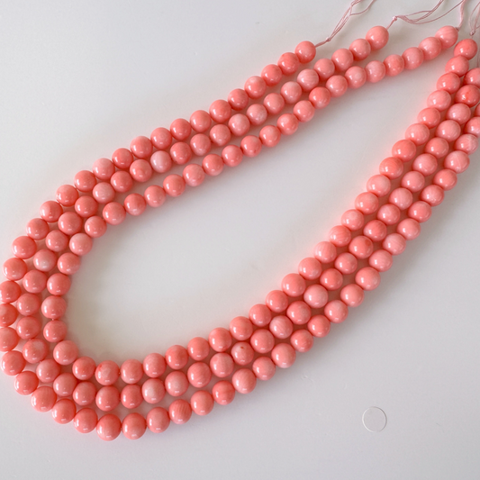 A necklace made of small, round, pink beads arranged in a row.