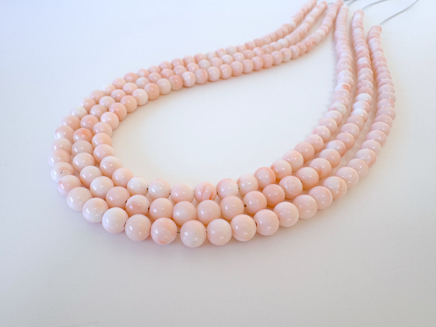 A necklace composed of numerous small, round beads in a light pink color.