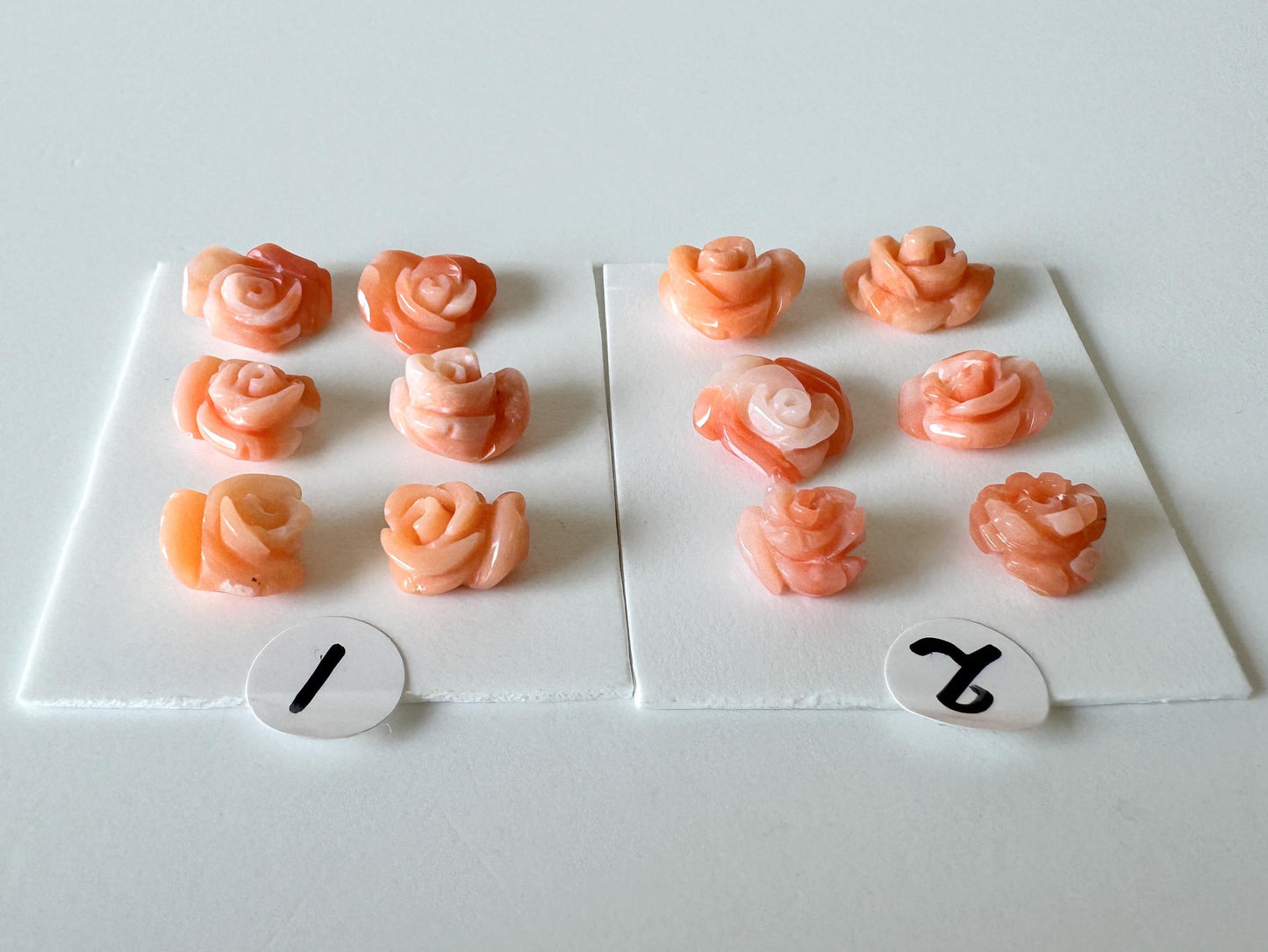 a collection of pink rose-shaped objects, each with a number attached to it. The numbers are 1 and 2, and they are placed on a white surface.