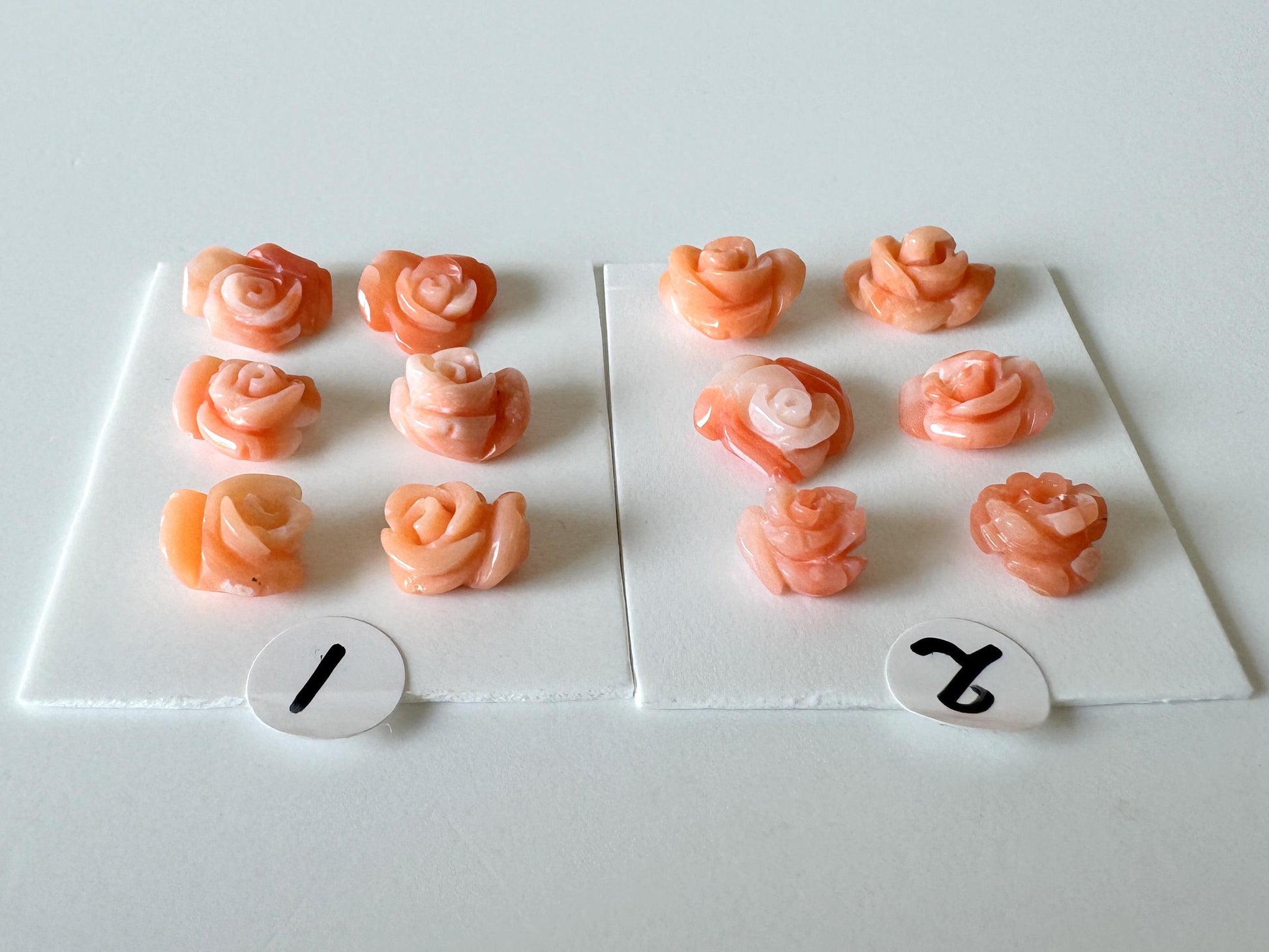 a collection of pink rose-shaped objects, each with a number attached to it. The numbers are 1 and 2, and they are placed on a white surface.