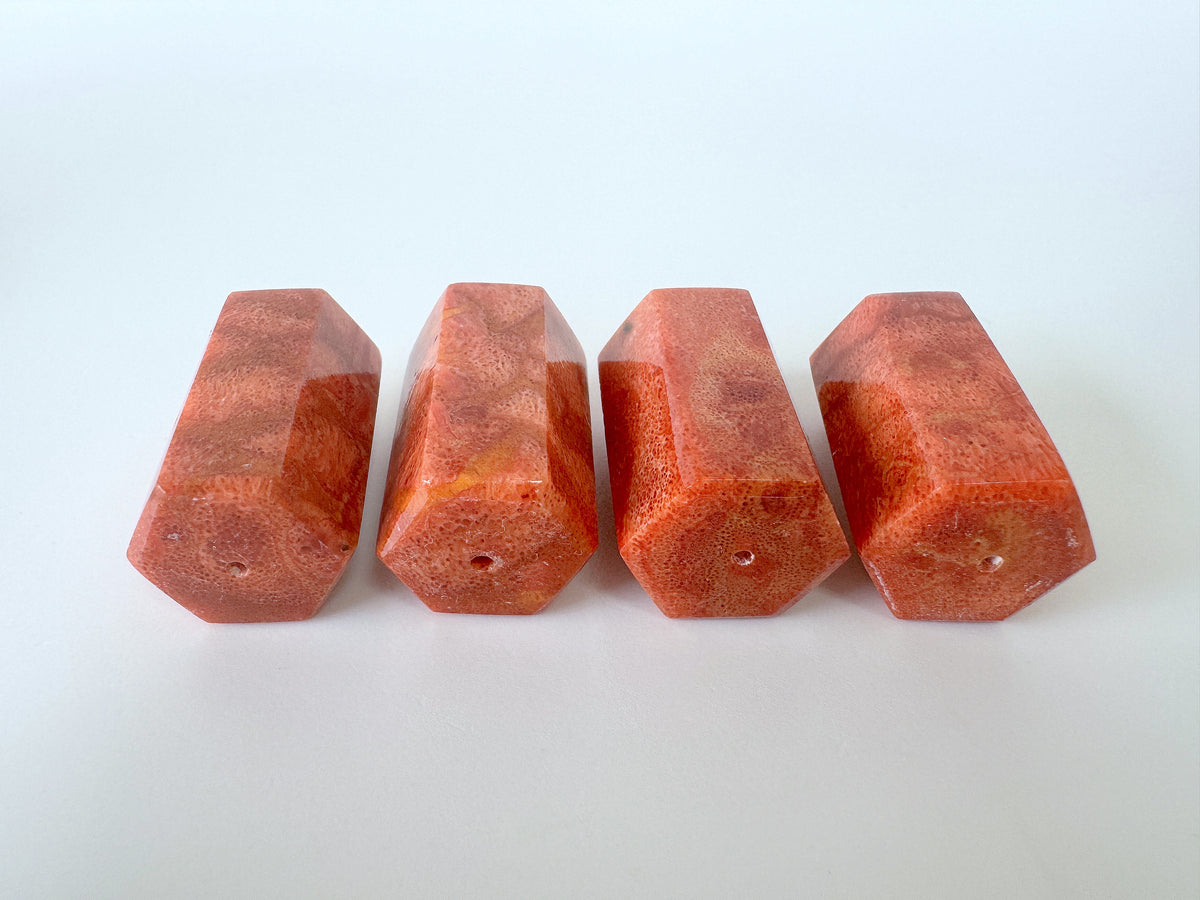 Four red, hexagonal-shaped objects are arranged in a row on a white background.