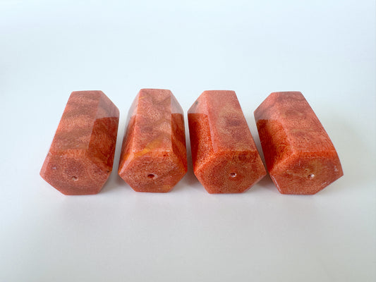 Four red, hexagonal-shaped objects are arranged in a row on a white background.