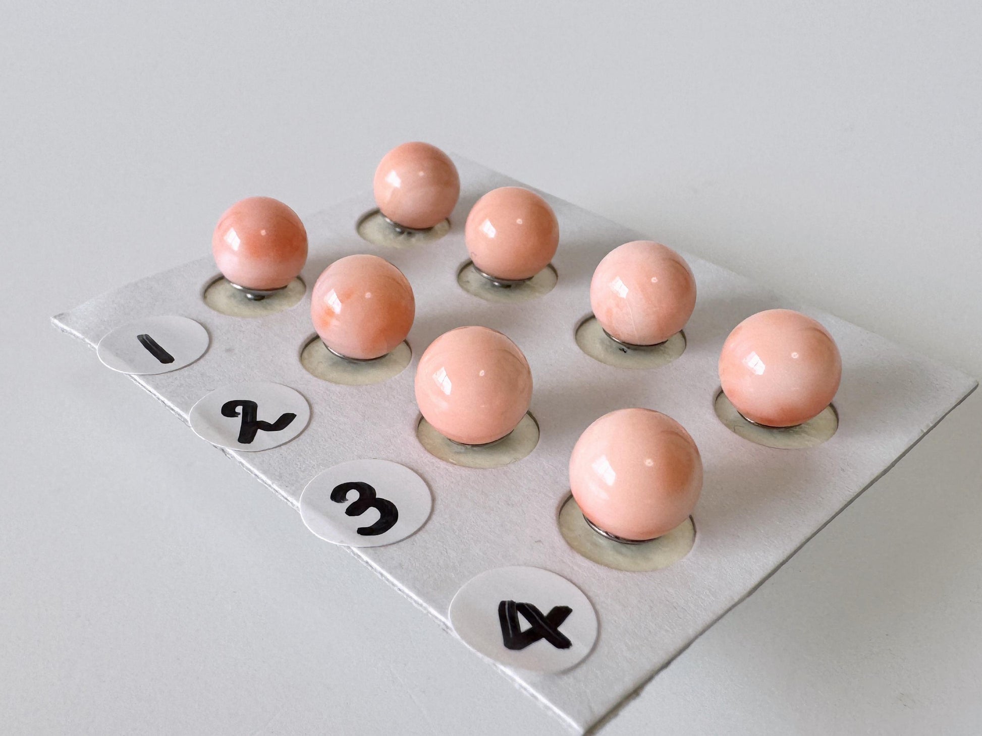 a group of nine small, round objects arranged in a grid-like pattern on a white surface.
