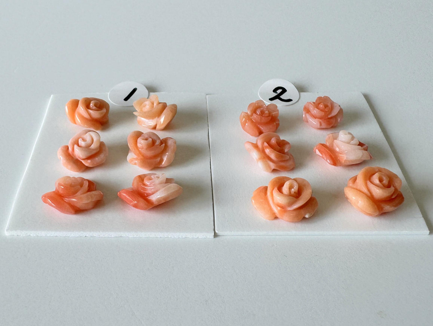 a collection of pink rose-shaped objects, each with a number attached to it. The numbers are 1 and 2, and the objects are arranged on two white boards.