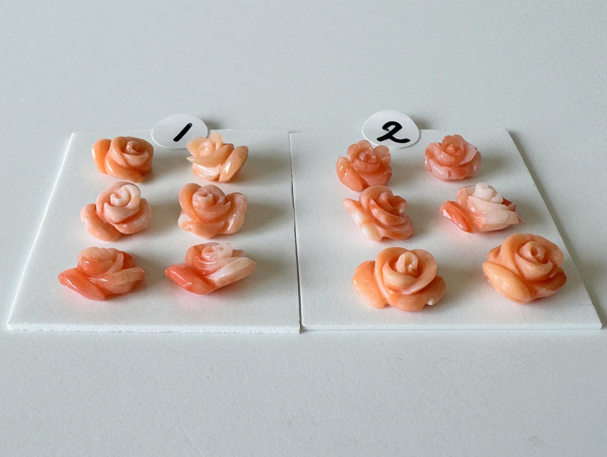 a collection of pink rose-shaped objects, each with a number attached to it. The numbers are 1 and 2, and the objects are arranged on two white boards.