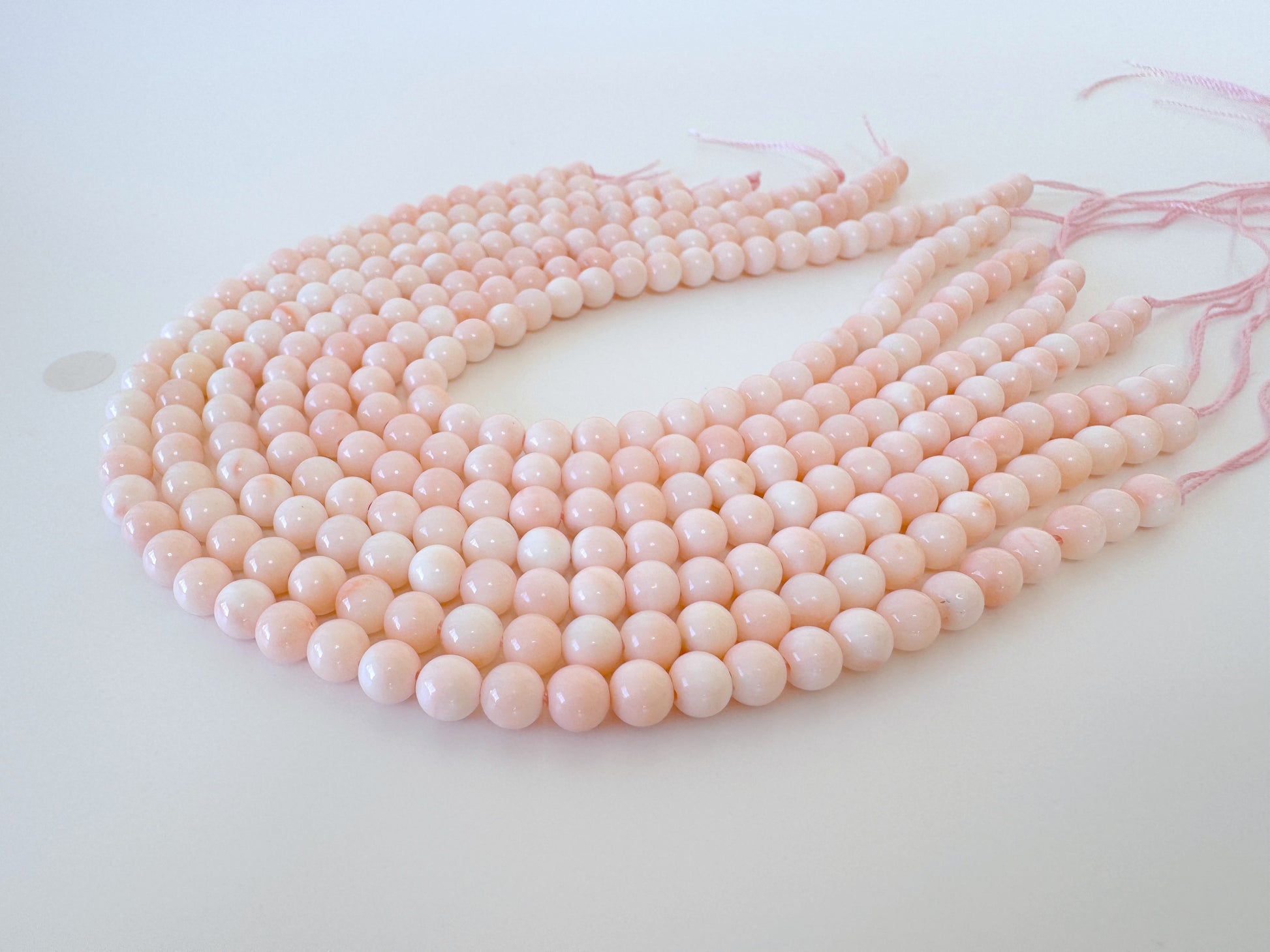 A collection of pink coral beads arranged in a circular pattern on a white background.