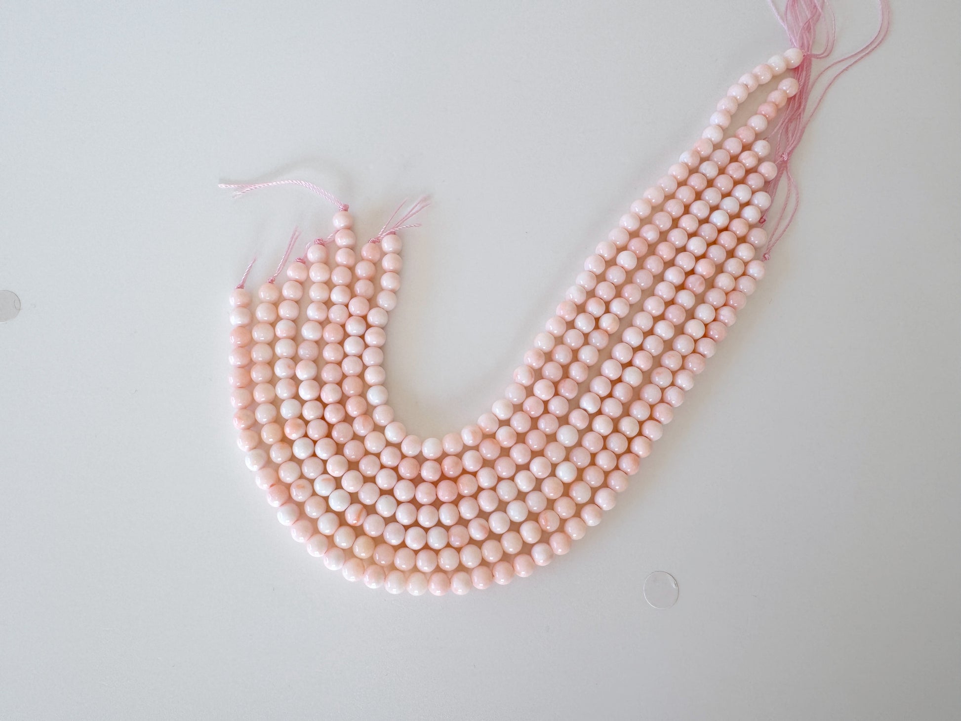 A collection of pink beads arranged in a curved pattern on a white background.