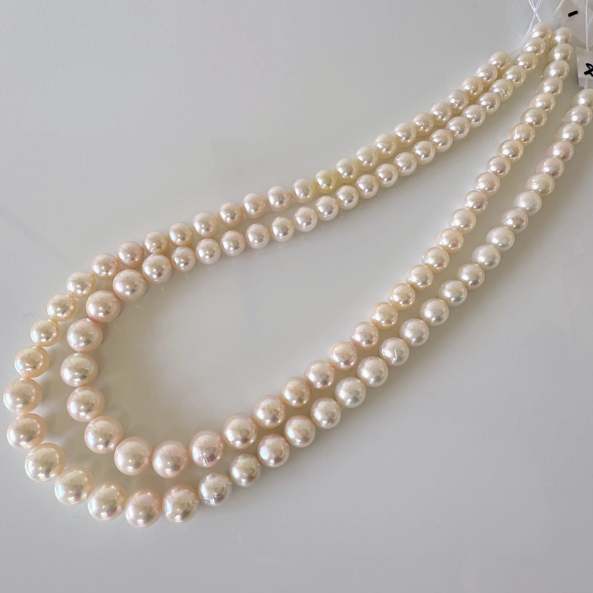 A necklace with three strands of white pearls is displayed on a white surface.