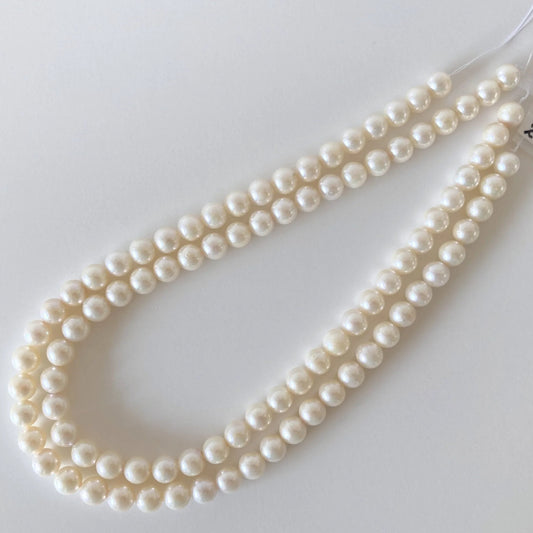 A necklace made of white pearls lying on a white surface.