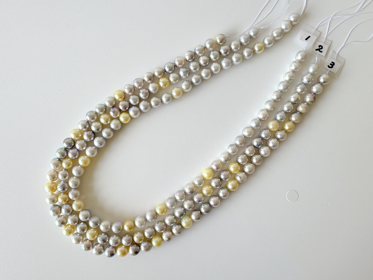 A necklace composed of multiple strands of beads, including white, yellow, and gray pearls, arranged in a decorative manner.