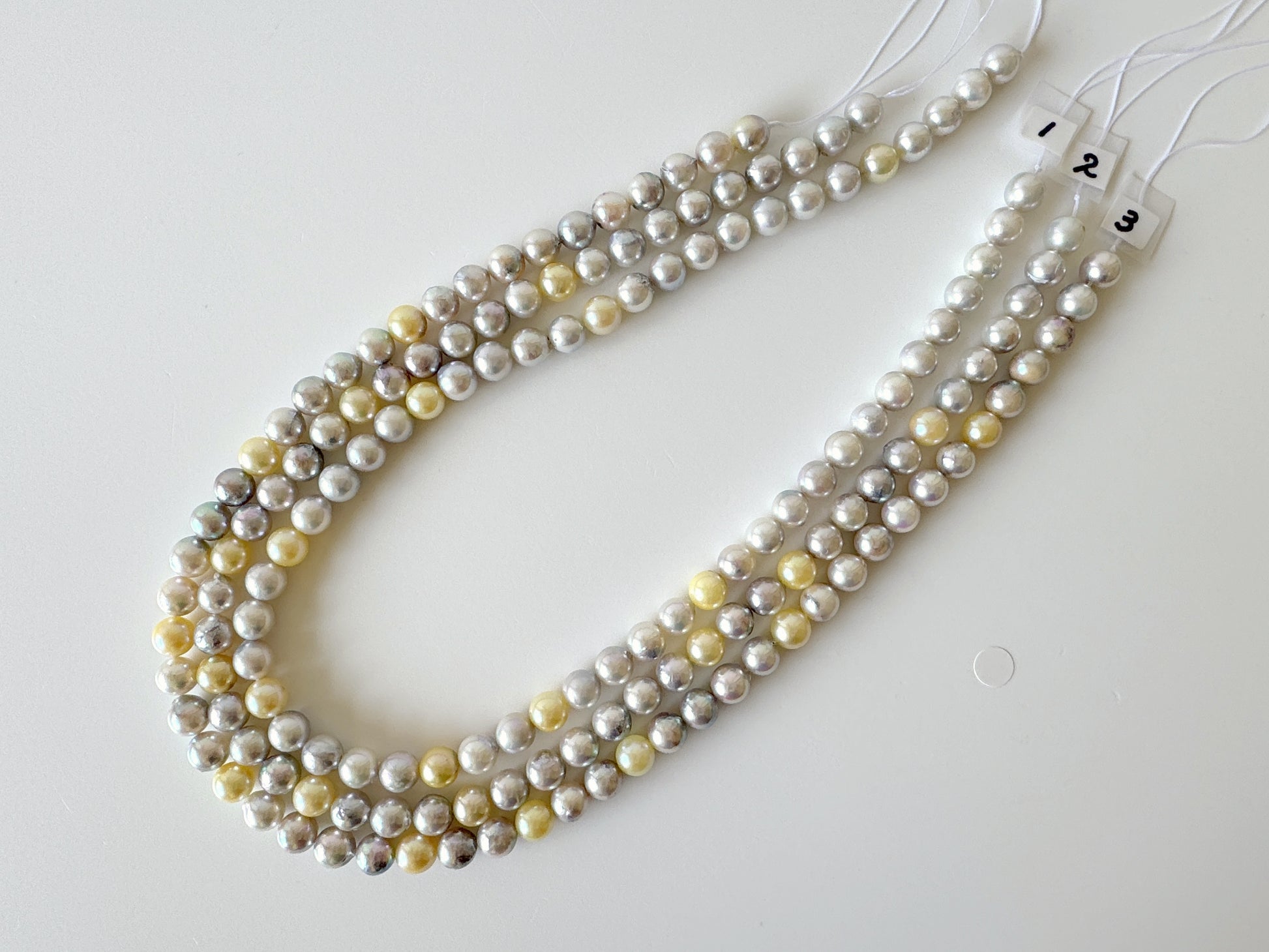 A necklace composed of multiple strands of beads, including white, yellow, and gray pearls, arranged in a decorative manner.