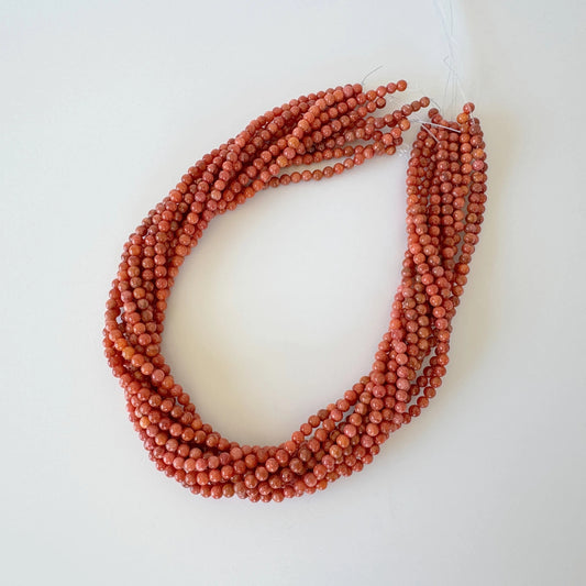 A necklace made of red beads is displayed against a white background.