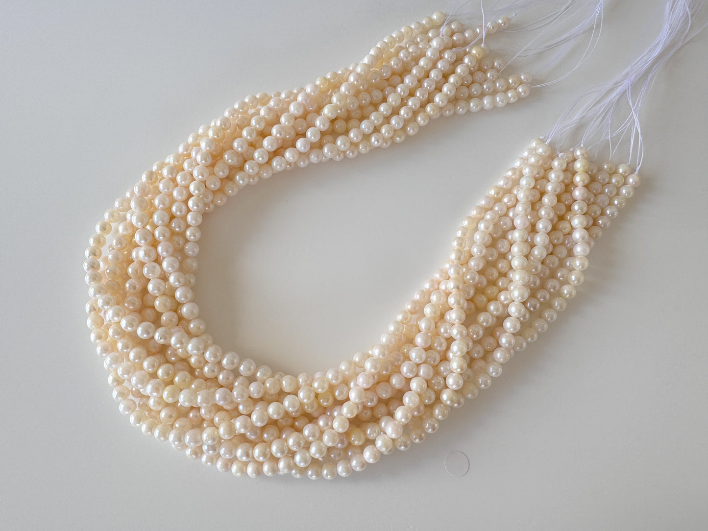 A necklace composed of numerous white pearls arranged in a circular pattern, with strings attached to the ends.