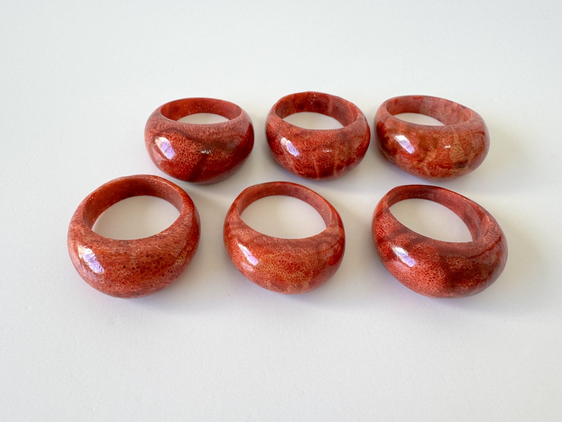 A group of six red, round, and oval-shaped objects arranged in two rows of three, likely representing a collection or a display.