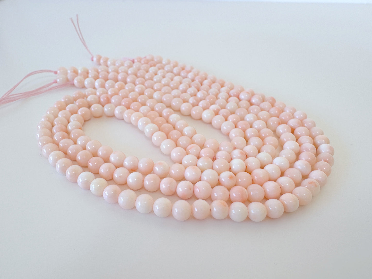 A group of pink and white beads arranged in a circular pattern on a white surface.