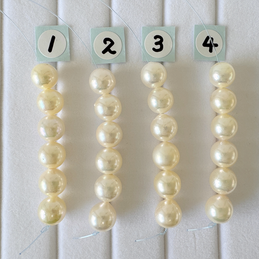 four rows of white pearls, each row numbered 1 through 4, with the numbers displayed on small square cards attached to the pearls.