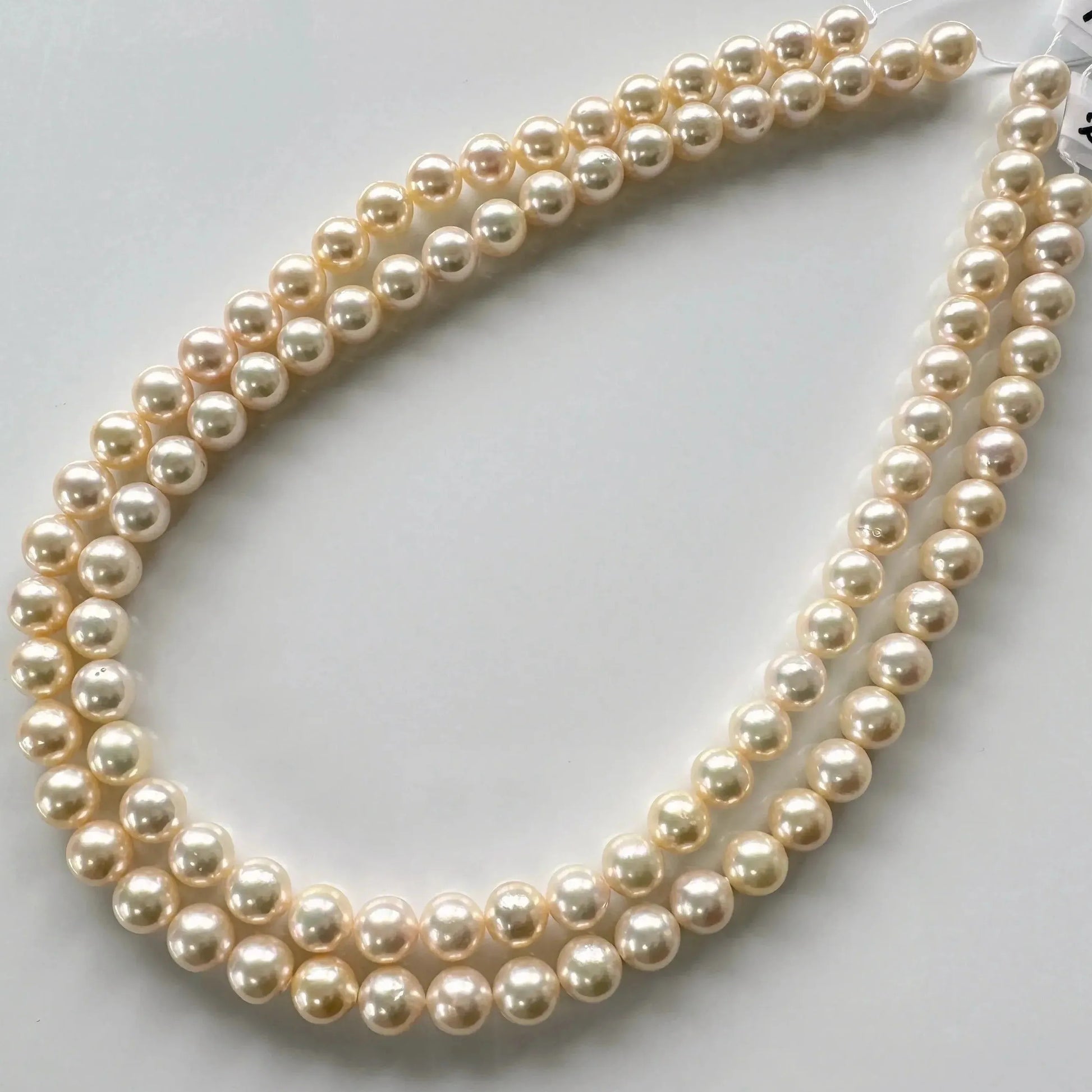 A necklace composed of multiple strands of white pearls is displayed on a white surface.