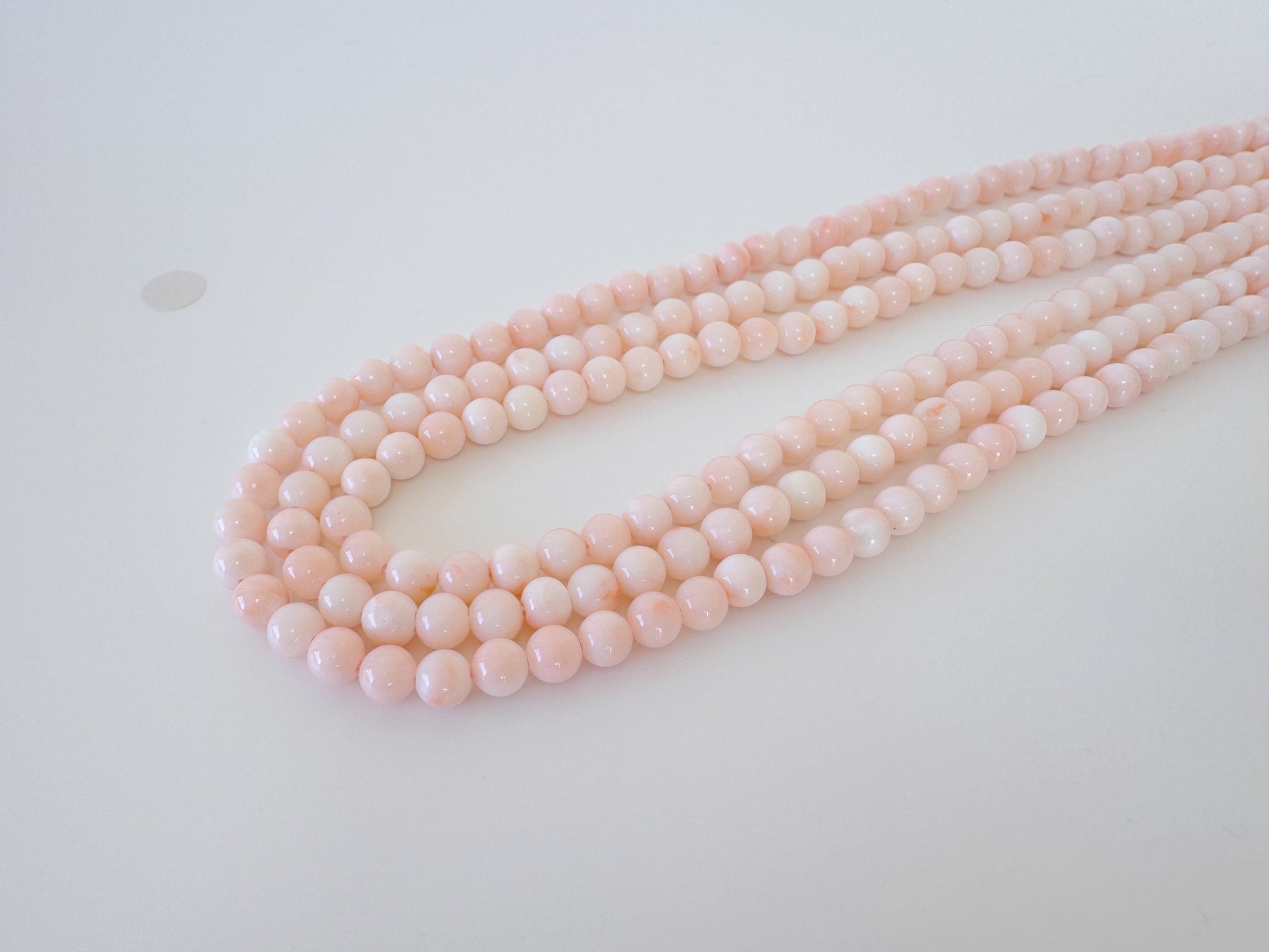 A necklace of pink beads arranged in a curved pattern on a white surface.