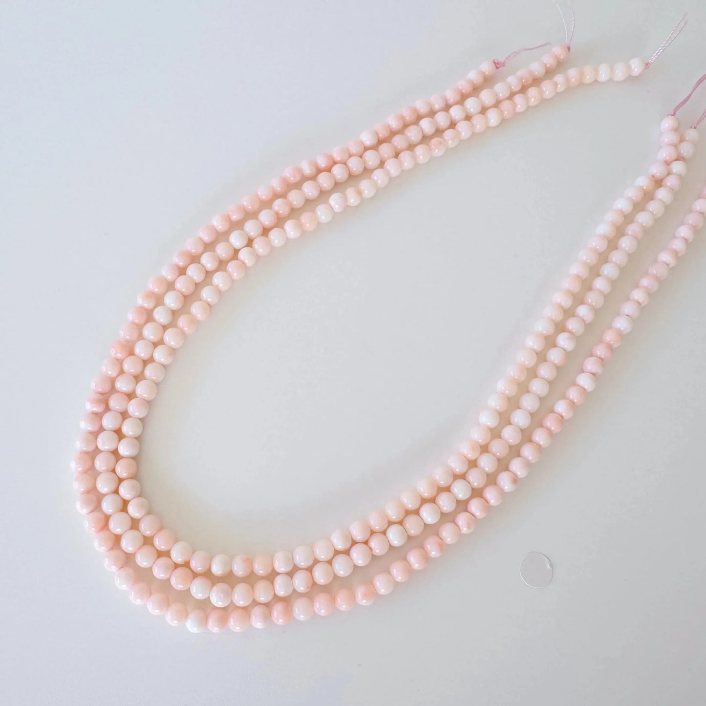 A necklace made of small, round beads in a light pink color.