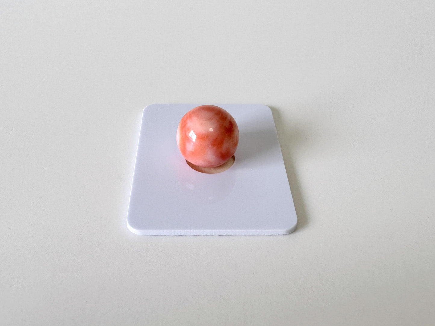 A single, round, red object is centered on a white surface.