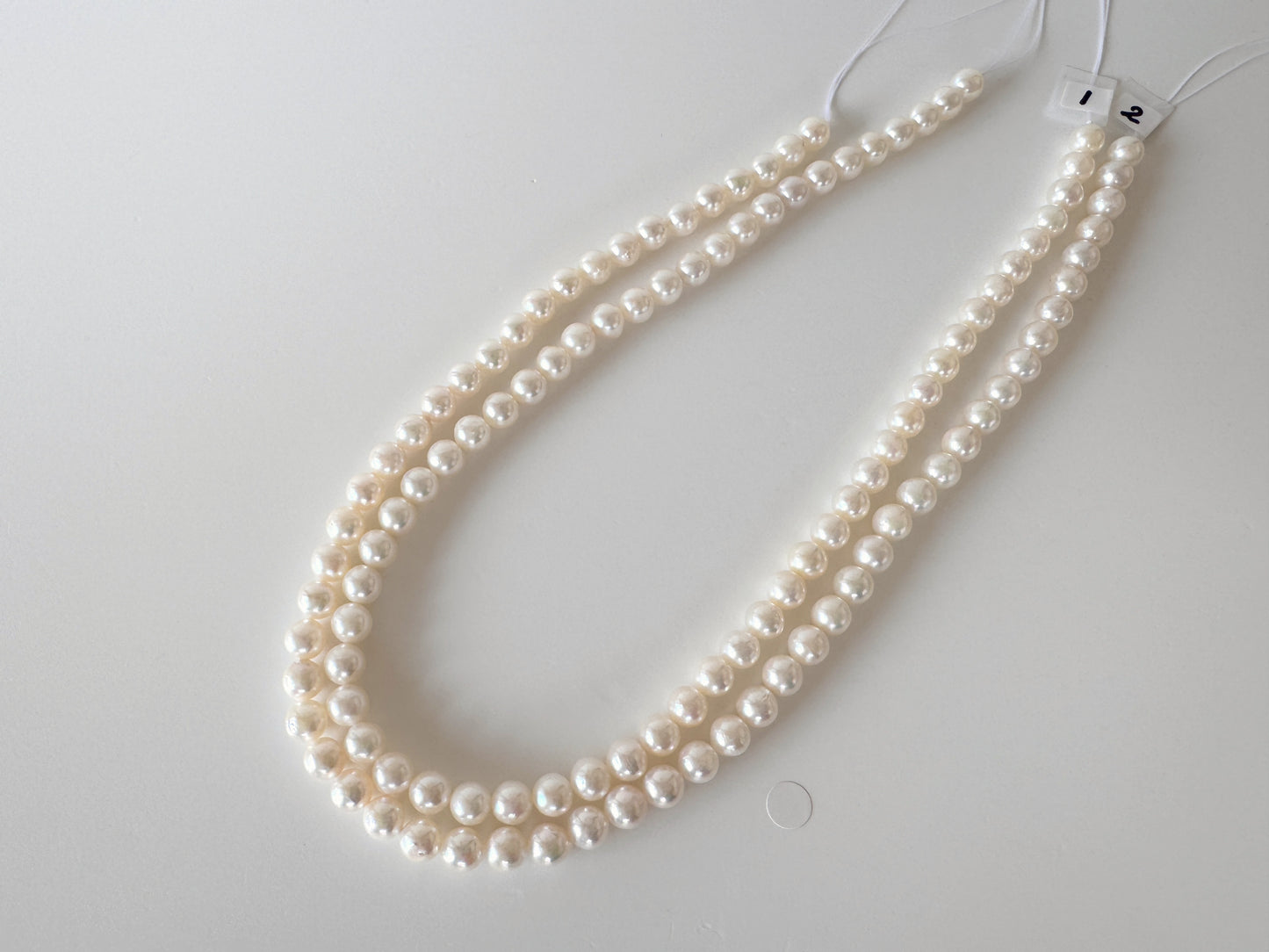 A necklace made of white pearls is displayed on a white surface.
