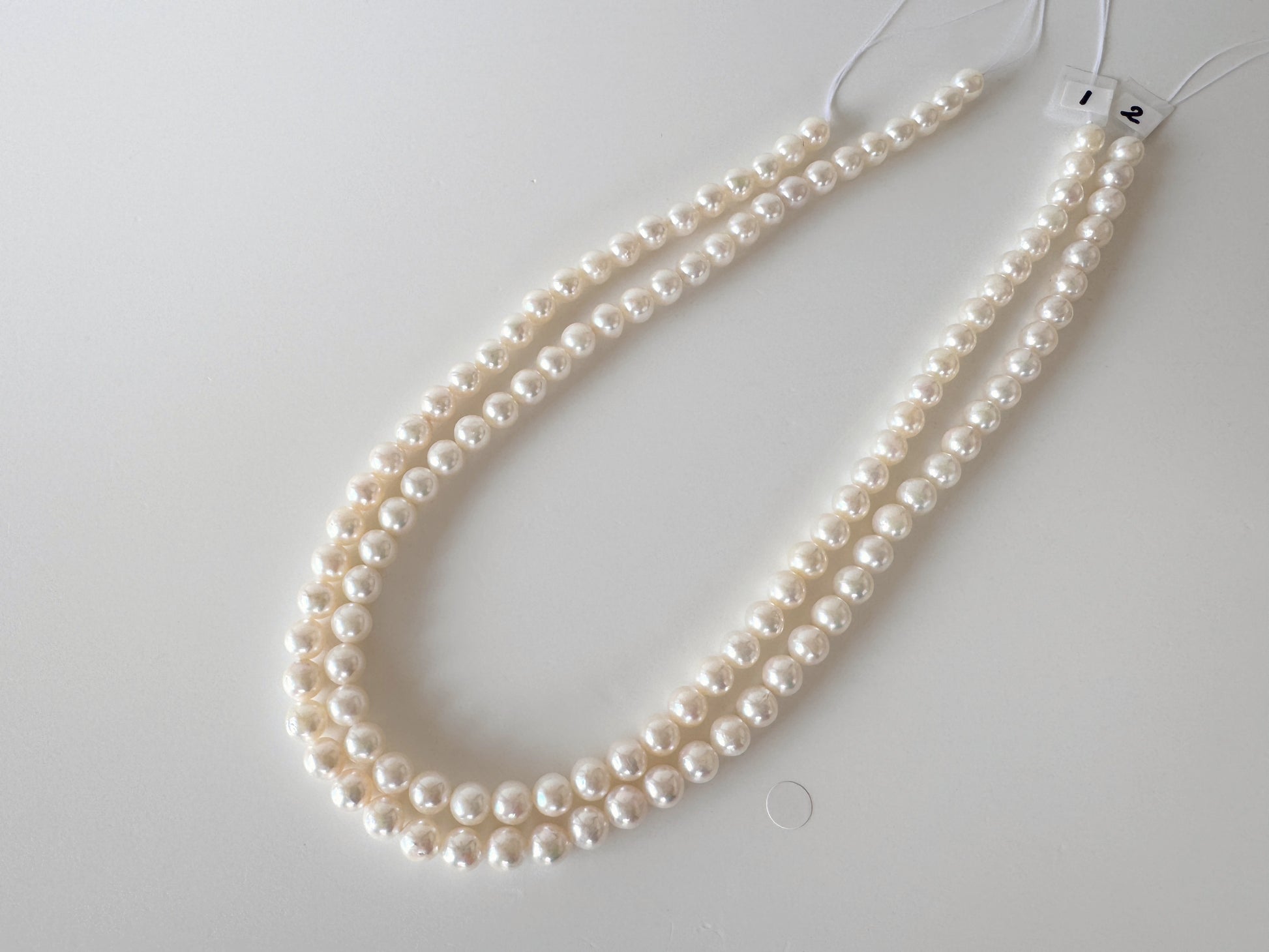 A necklace made of white pearls is displayed on a white surface.