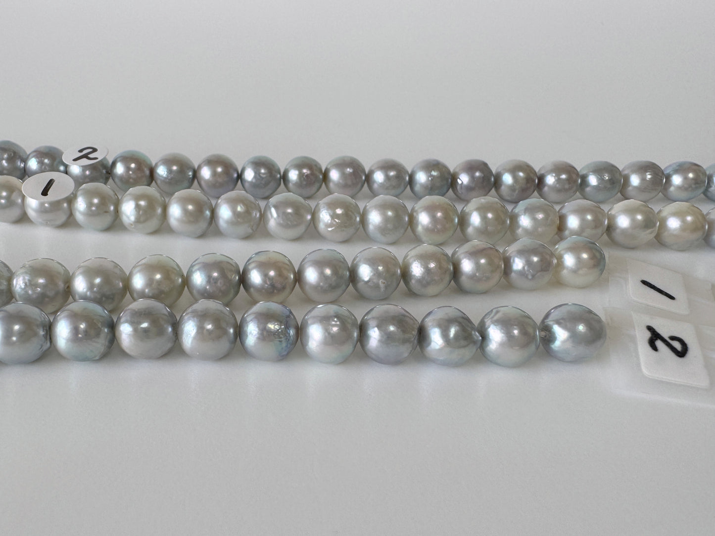 a collection of numerous silver and white pearls arranged in rows on a white surface.